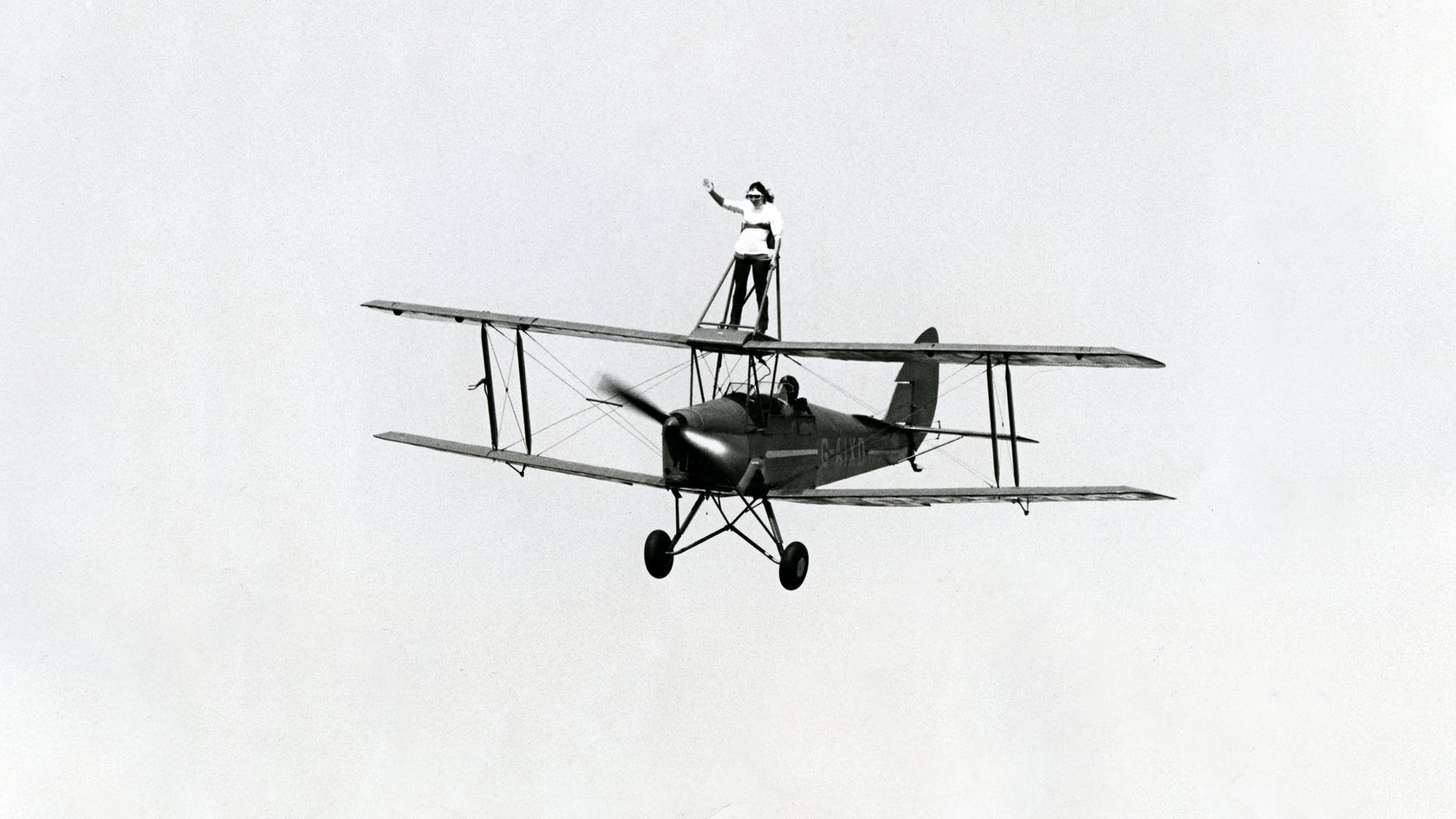Photo Archiv Schweizer: Schwarz-Weiß-Foto mit altem Doppeldecker-Flugzeug mit stehender Frau auf dem oberen Flügel