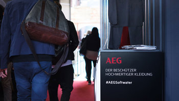 Stele mit Designermode. Aufschrift: Kampagnen-Motto „AEG – der Beschützer hochwertiger Kleidung“