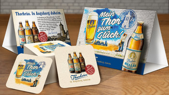 [Translate to EN:] Thorbräu Werbemittel mit Kampagnen Motiv und Packaging - Tischaufsteller und Bierdeckel