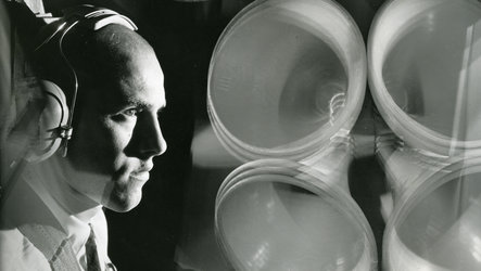 Mann mit Kopfhörern vor Lautsprecherwand - schwarz/weiß Bild aus dem Schweizer Archiv